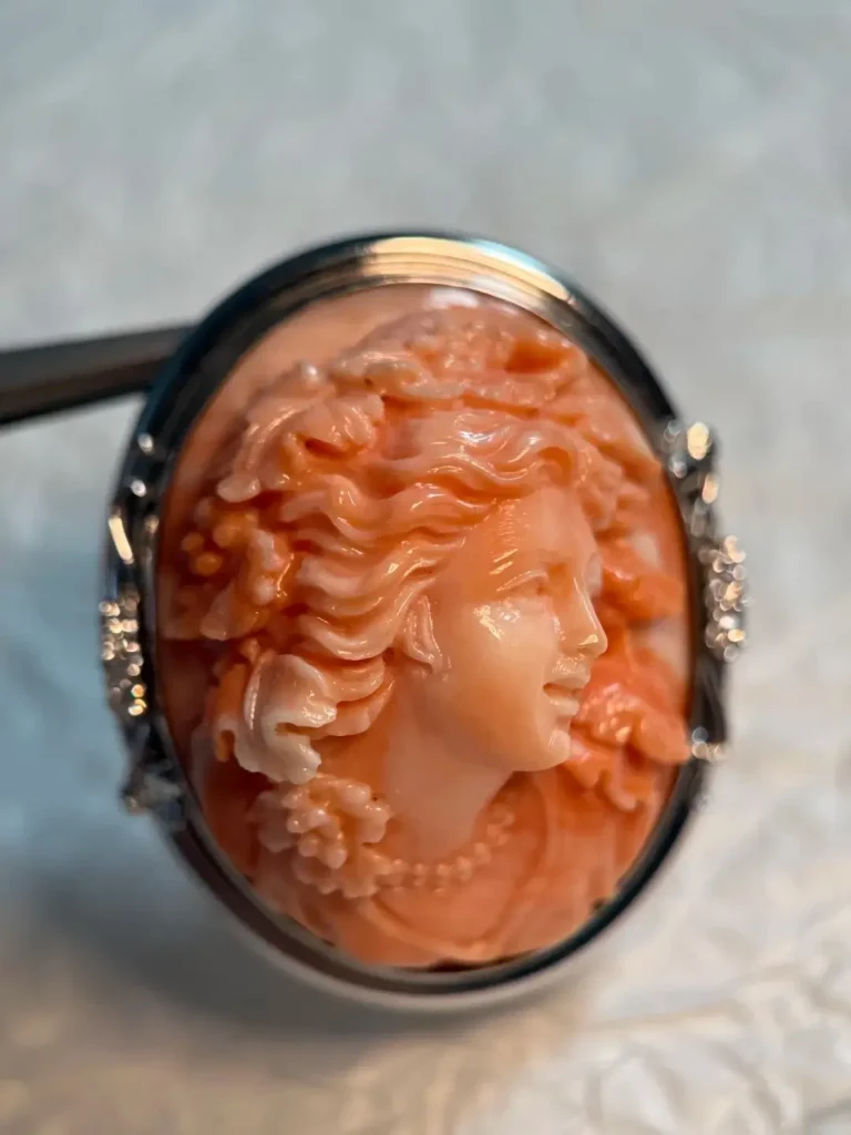 Pink coral cameo brooch pendant featuring a carved Bacchus figure in a platinum diamond setting.