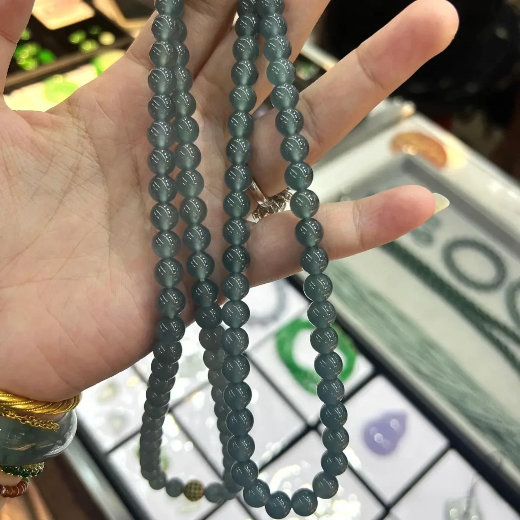 A blue-water Guatemalan jadeite bead necklace displayed over a hand.