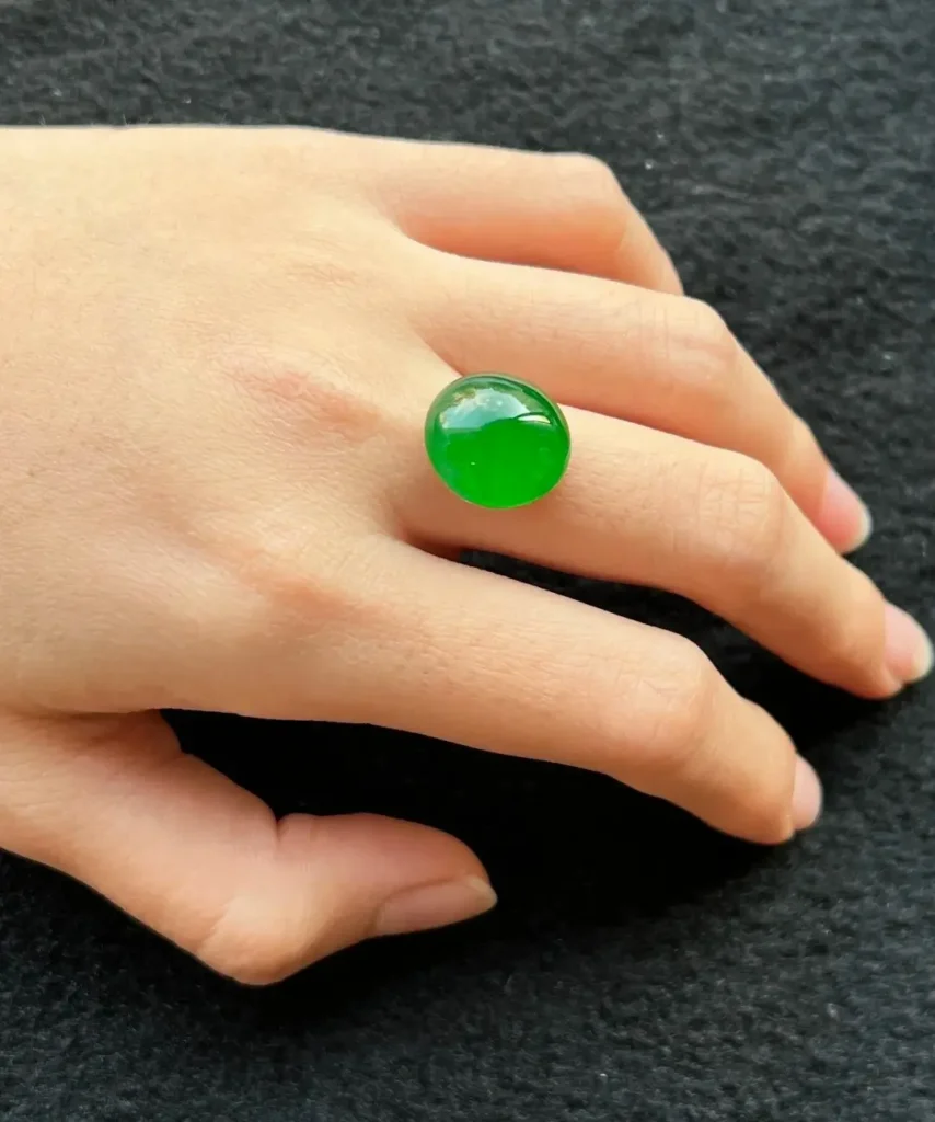 A green cabochon displayed on a hand under natural light.