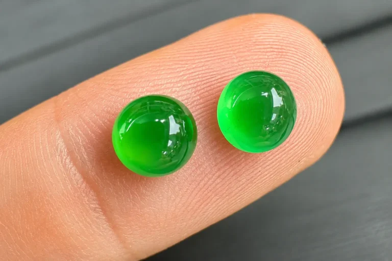 Two green Guatemalan jadeite cabochons placed on an index finger for display.