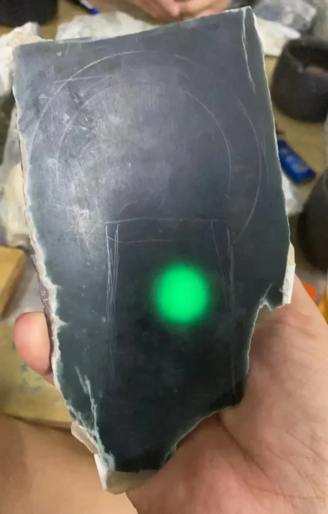 A dark green Mocui jadeite slab showing a gray-green tone under transmitted light.
