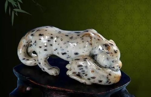 Hetian jade leopard carving using natural dark mineral spots as realistic coat patterns.