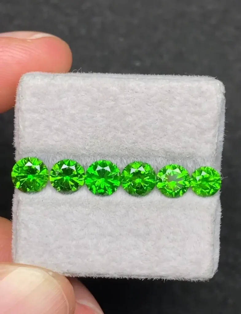 Six Iranian demantoid garnet round faceted gemstones with vivid green color.