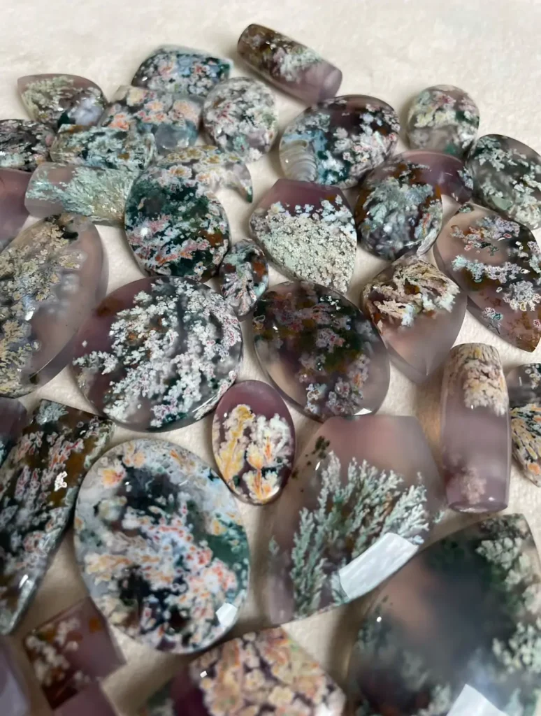 Collection of Iranian plume agates with green, white, and orange floral-like patterns.