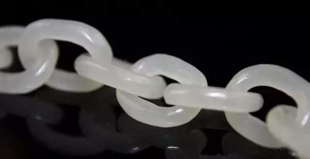 Close-up of hand-carved white jade interlocking rings forming a movable chain.
