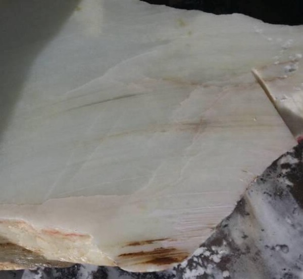 Raw mountain Hetian jade showing multiple internal fractures within the cut stone.