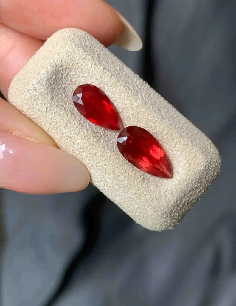 Two faceted red gemstones shown side by side with similar color and appearance.