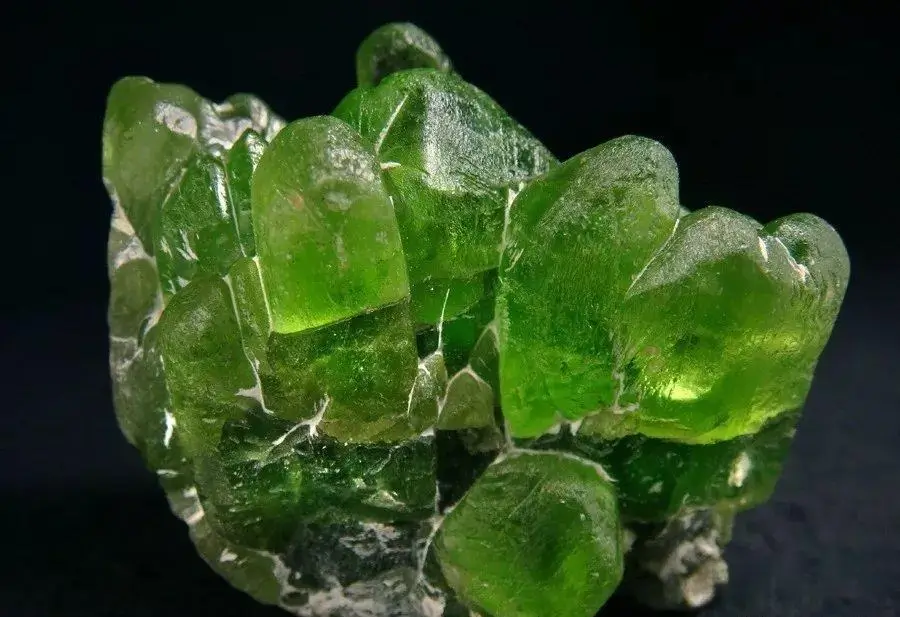 Green Peridot rough crystals from Pakistan displayed against a dark background.