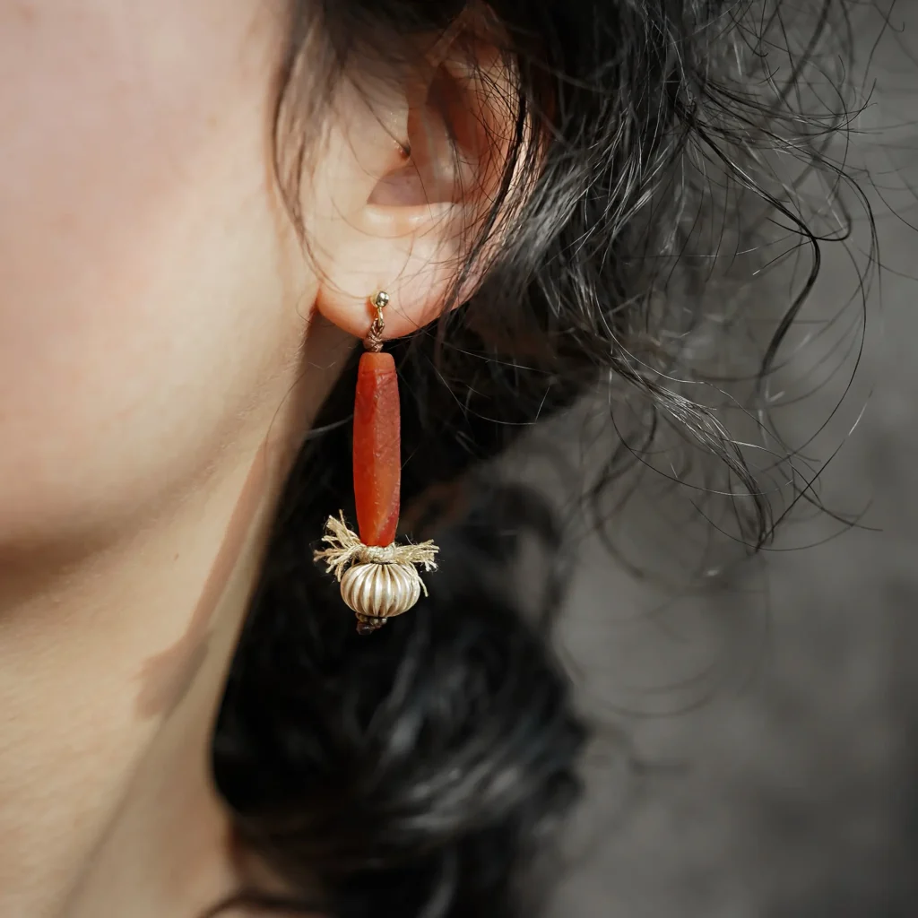 Model wearing a handmade red agate dangle earring with white copper on her left ear.