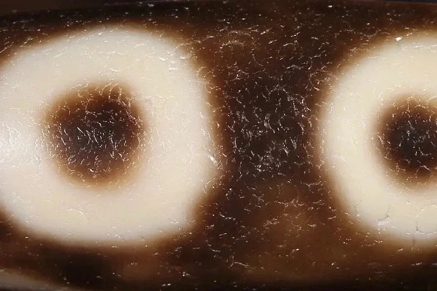 Close-up of an old Dzi bead with subtle crescent-shaped weathering marks