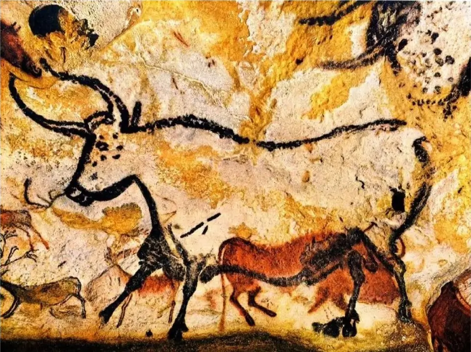 Prehistoric cave painting of a large bull and other animals in dark and ochre natural mineral pigments.