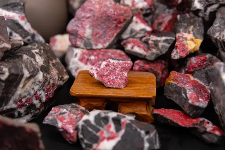 Raw cinnabar ore specimens with bright red areas displayed on and around a wooden stand.