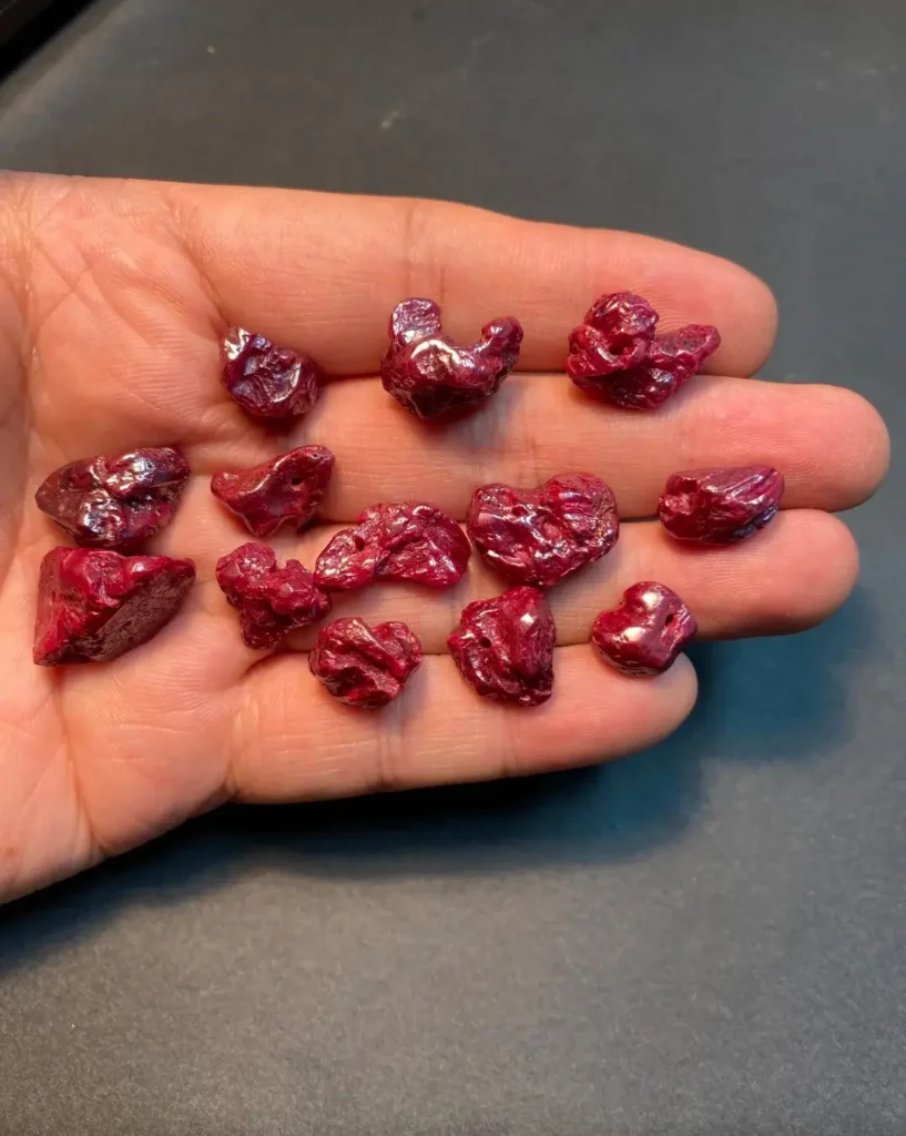 Small irregular deep-red cinnabar pieces held in an open palm.