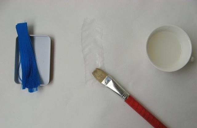 A soft flat brush applying a strip of starch paste to Xuan paper.