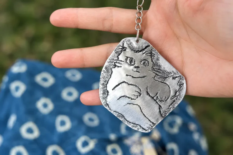 A cat pendant hand-carved from an aluminum sheet.