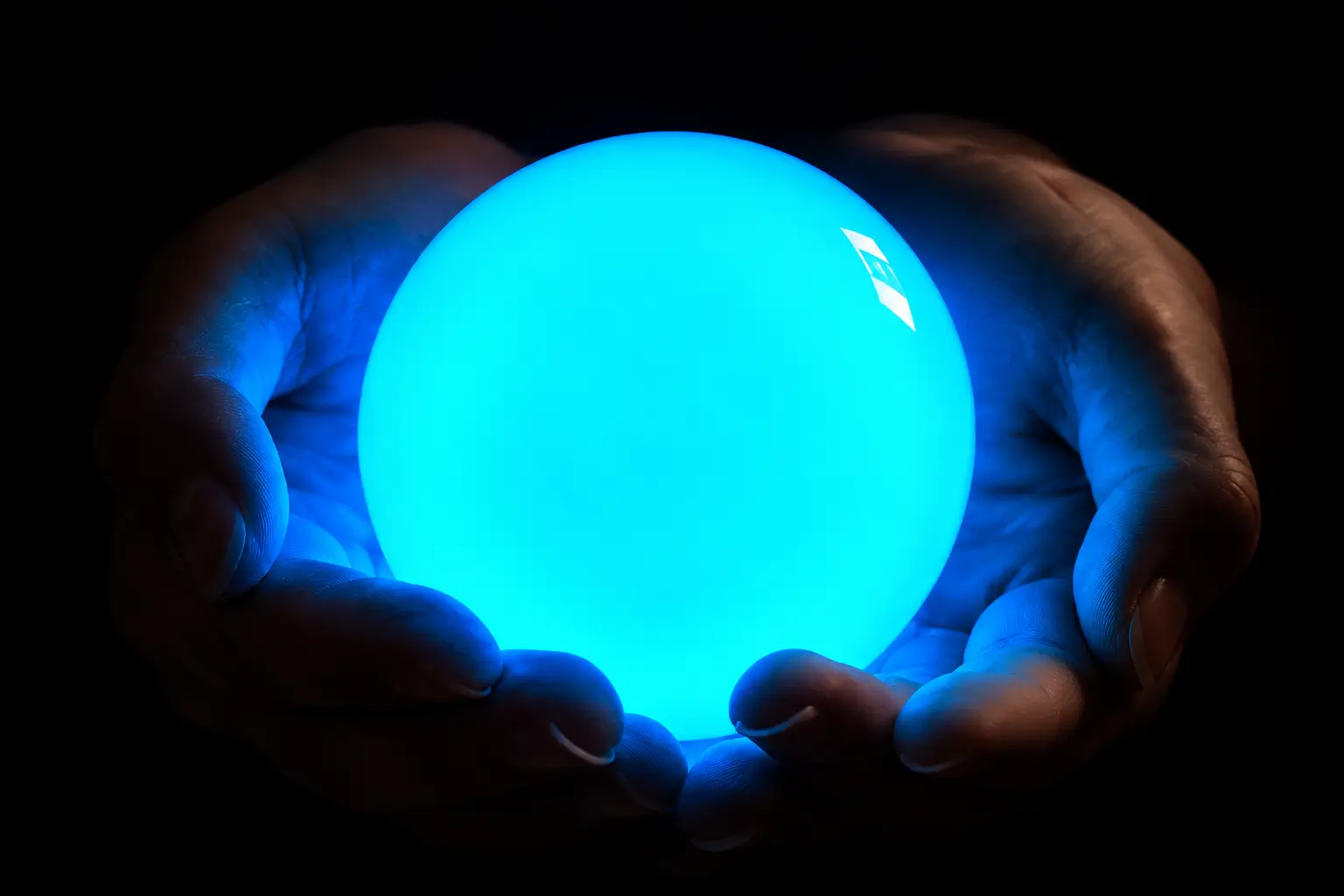 Hands holding a night-shining pearl emitting a blue-green glow in the dark.