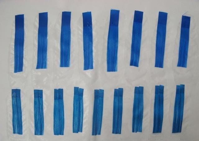 Blue ribbon strands coated with starch paste resting on Xuan paper to dry partially.