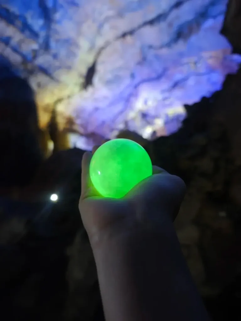 A hand holding an imitation night-shining pearl made from strontium aluminate material.