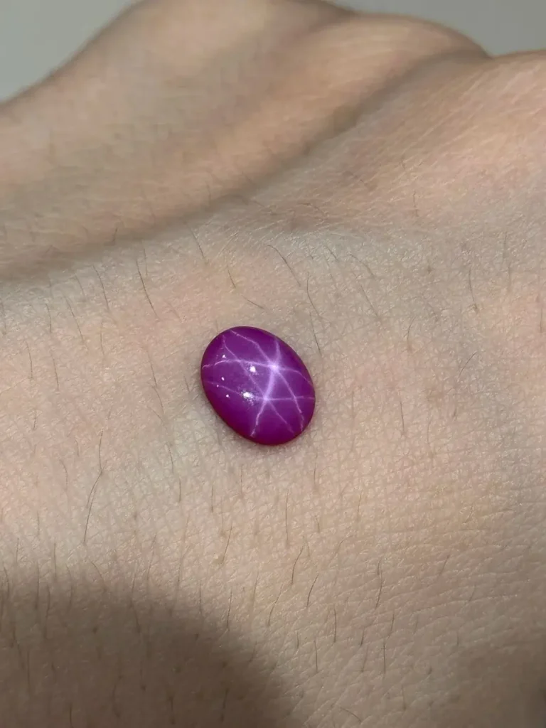 A synthetic purple star sapphire with no central star, thin uneven rays, and a star that appears static when rotated.